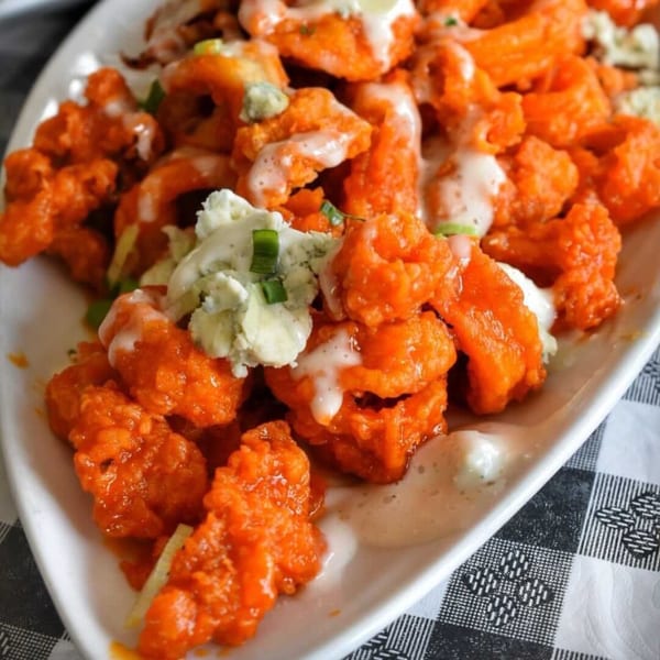 A close-up of Charred Brick Oven's buffalo shrimp appetizer with blue cheese crumbles and ranch dressing.