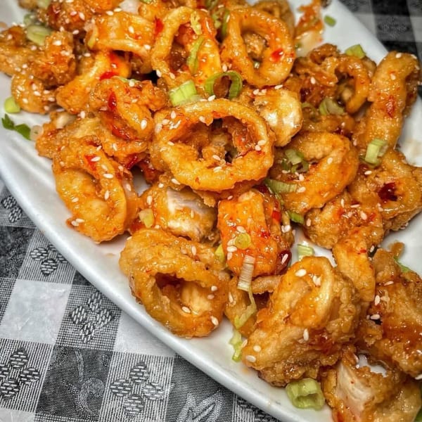 Crispy fried calamari rings and pieces, glazed with a sweet chili sauce, garnished with sesame seeds and green onions.